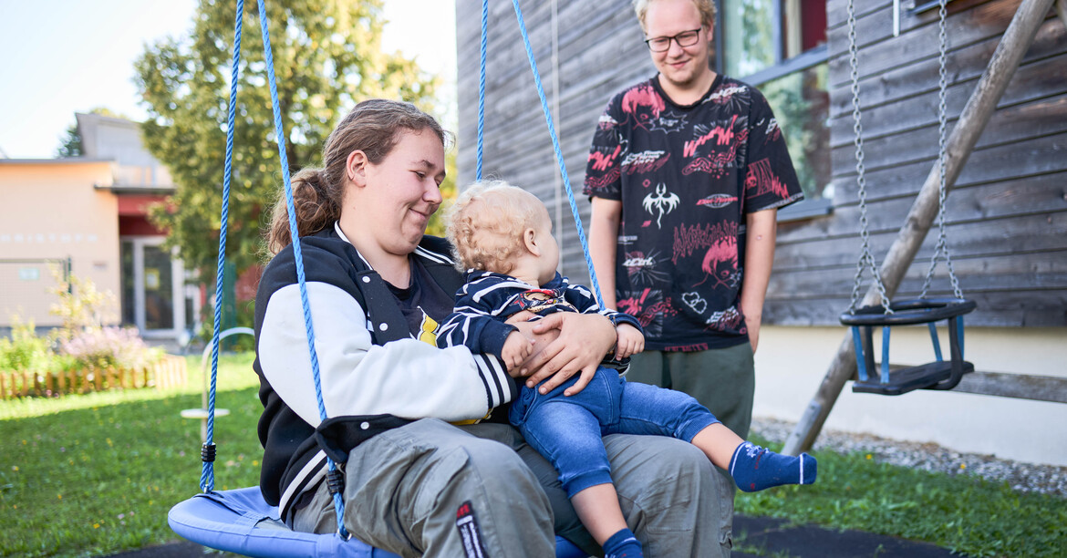 Eine Jungfamilie im Garten vorm Familienhaus St. Christoph