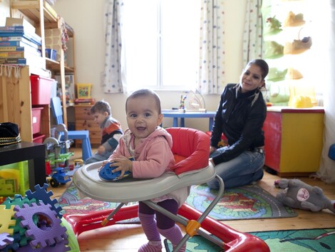 Zwei Kleinkinder mit einer Mutter in einem Spielraum
